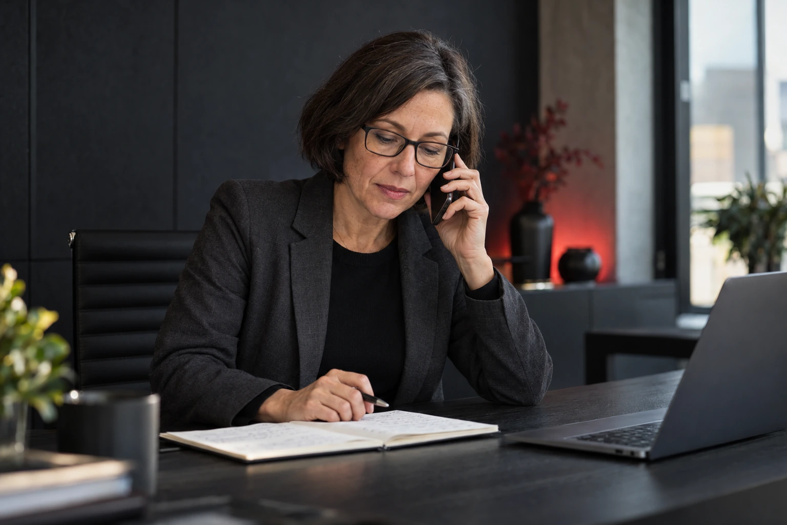 Eine erfahrene Vertriebsmitarbeiterin hört bei einem Telefonat aufmerksam zu und hält Notizen für das Gespräch bereit.